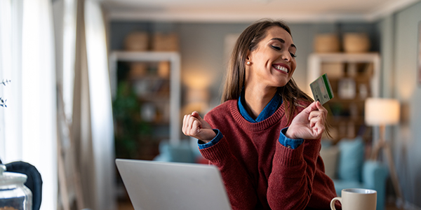 woman sitting in front of a laptop holding a card